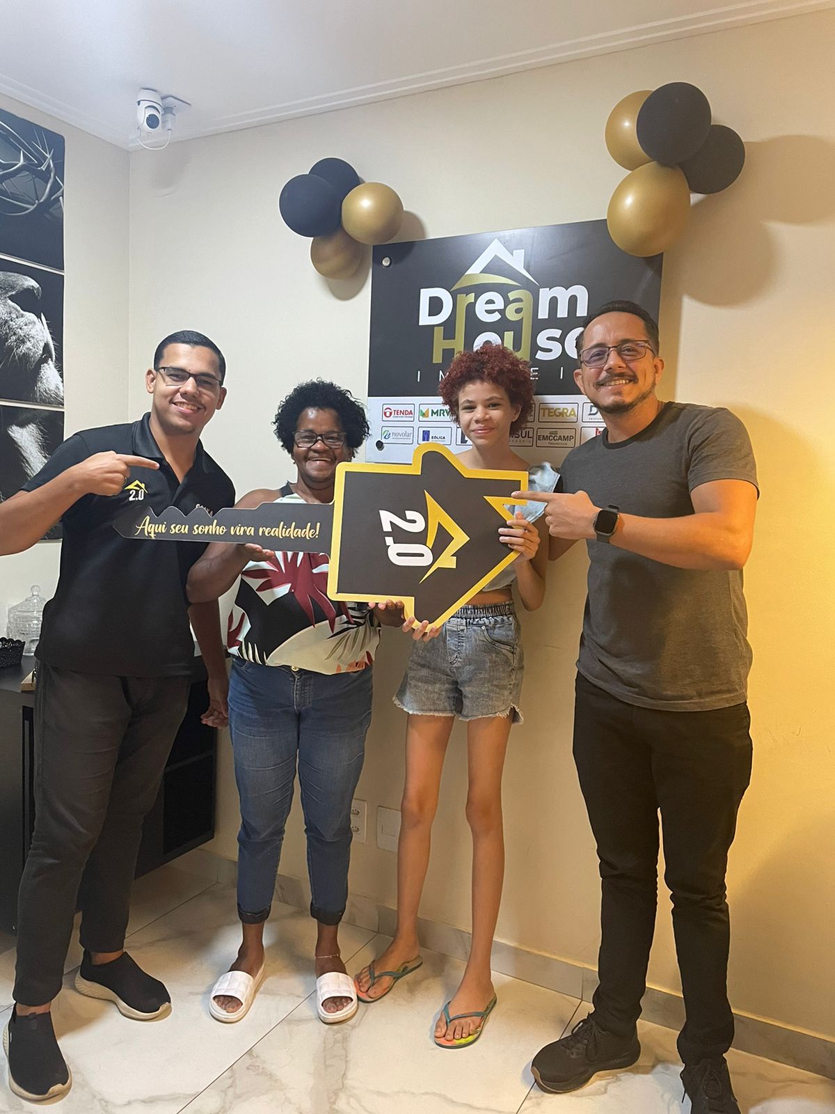 Família feliz em frente à sua nova casa em um bairro em desenvolvimento.